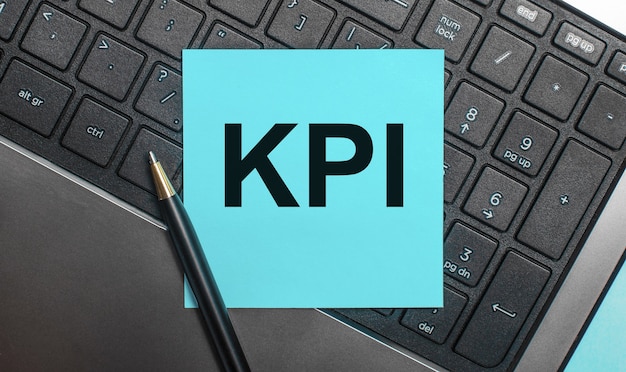 Le clavier de l'ordinateur a un stylo et un autocollant bleu avec le texte KPI. Mise à plat.