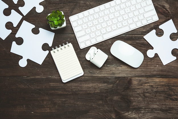 Clavier et pièces de puzzle blanc sur un fond en bois brun, vue du dessus