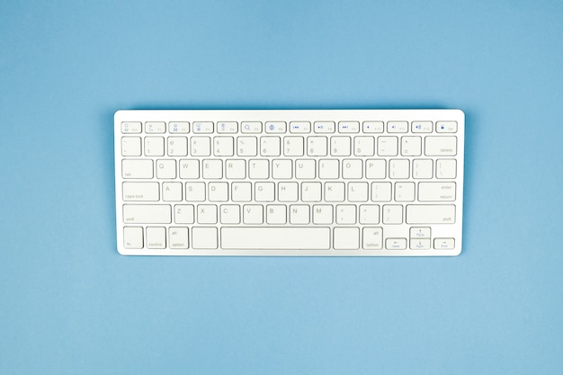 Clavier sans fil blanc compact sur fond bleu.