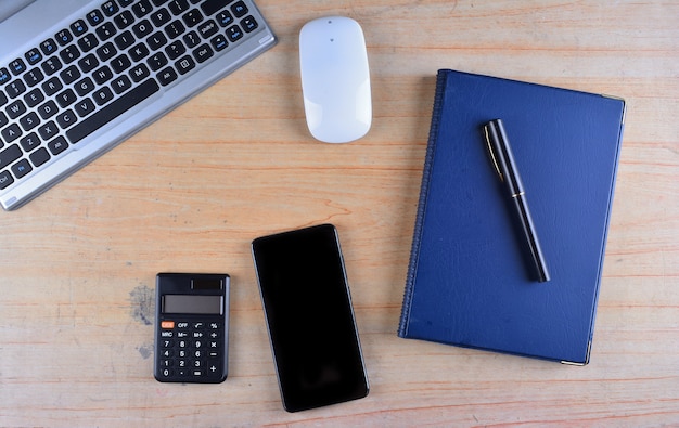 Clavier et souris, stylo plume, bloc-notes, calculatrice et smartphone sur une table