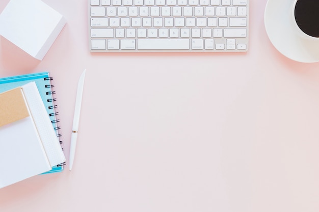 Photo clavier et tasse de café près de papeterie sur un bureau rose