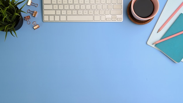 Clavier, tasse et cahier sur table bleue