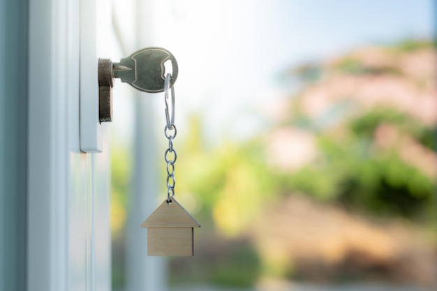 La clé du propriétaire pour déverrouiller la maison est branchée dans la porte maison de seconde main à louer et à vendre porte-clés souffle dans le vent hypothèque pour une nouvelle maison acheter vendre rénover investissement propriétaire immobilier