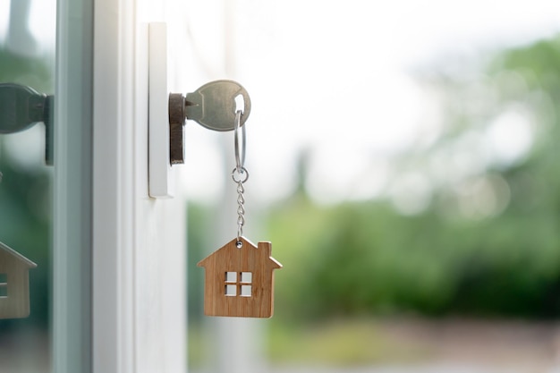 La clé du propriétaire pour déverrouiller la maison est branchée sur la porte La maison d'occasion à louer et à vendre le porte-clés souffle dans le vent l'hypothèque pour la nouvelle maison acheter vendre rénover l'investissement propriétaire immobilier