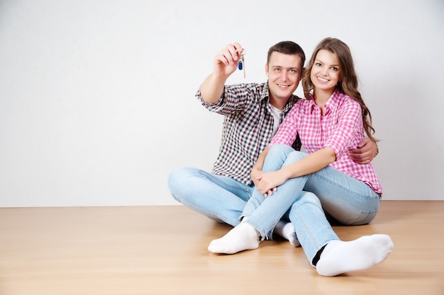 Clé de leur nouvelle maison. Heureux jeune couple debout près l&#39;un de l&#39;autre et souriant tout en maintenant la clé de la maison