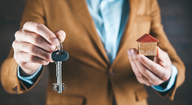 Clé de main de l'homme et modèle de maison sur dark