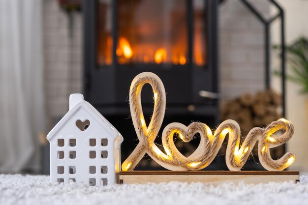 La clé de la maison avec porte-clés sur le fond de la cheminée poêle avec feu et bois de chauffage dans la décoration de la Saint-Valentin amour maison déménager dans une nouvelle maison prêt hypothécaire louer et acheter de l'immobilier