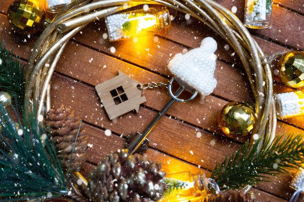 Clé de la maison avec un porte-clés petite maison sur fond de bois avec disposition de décoration de Noël