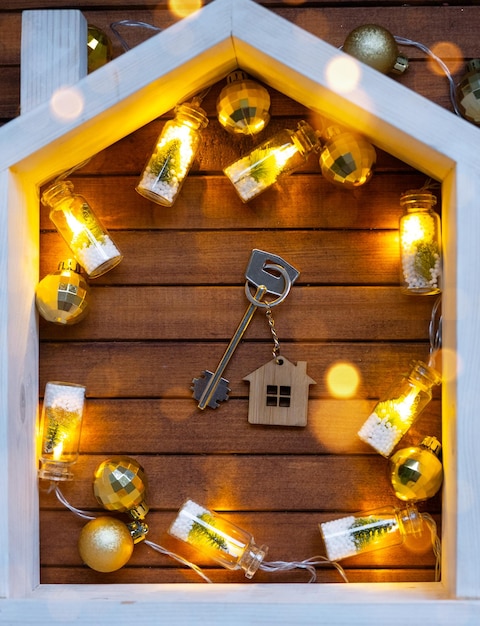 Clé de la maison avec un porte-clés petite maison sur fond de bois avec disposition de décoration de Noël