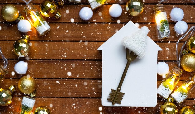 Clé de la maison avec un porte-clés petite maison sur fond de bois avec disposition de décoration de Noël