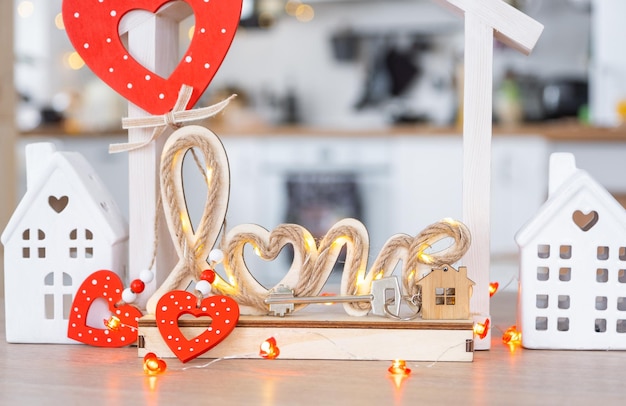 La clé d'une petite maison confortable avec une décoration de la Saint-Valentin sur la table de la cuisine Cadeau pour la Saint-valentin projet de conception de nid d'amour familial déménagement dans une nouvelle maison prêt hypothécaire loyer et achat d'immobilier