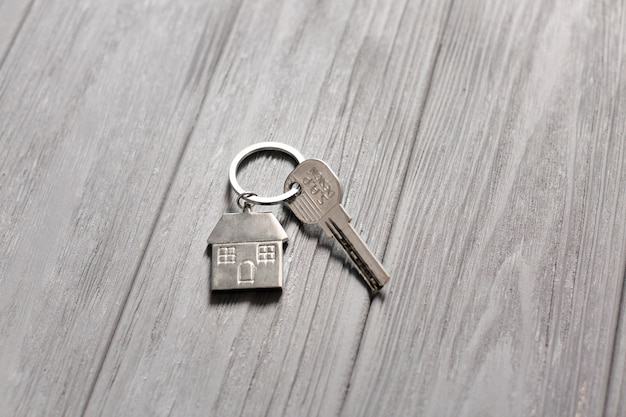 Photo clé avec petite maison sur la table en bois