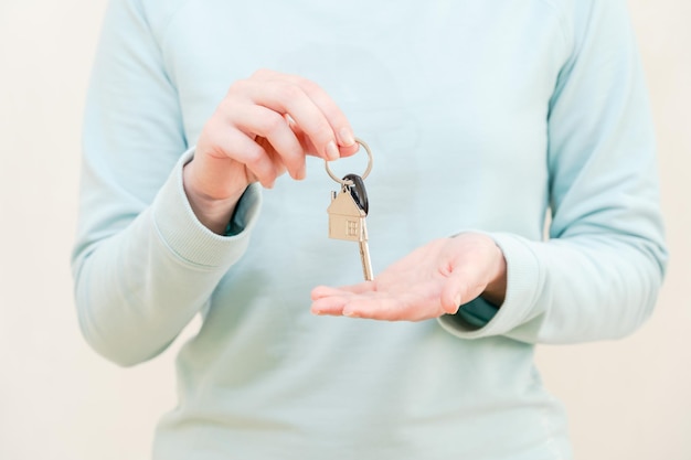 Clé avec porte-clés en forme de maison en mains