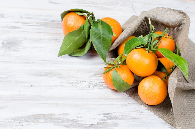 Clémentine de mandarines avec des feuilles sur une table en bois.