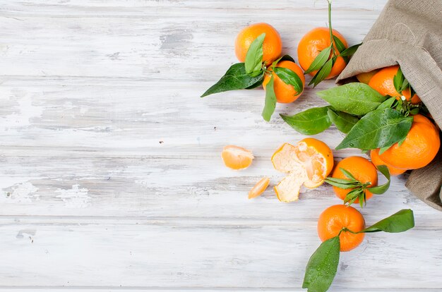 Clémentine de mandarines avec des feuilles sur une table en bois.