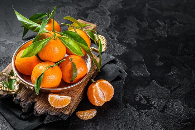 Clémentines Mandarines aux feuilles vertes. Fond noir. Vue de dessus. Espace de copie.