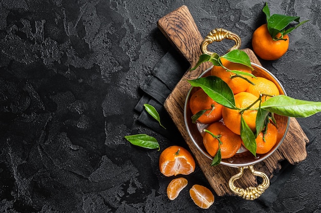 Clémentines Mandarines aux feuilles vertes Fond noir Vue de dessus Espace de copie