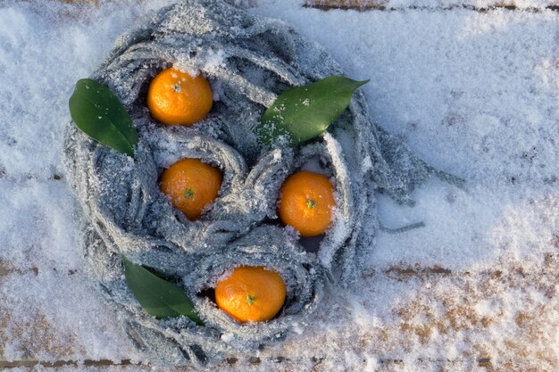 Clémentines mandarines avec des feuilles comme décor de Noël sur fond de neige.