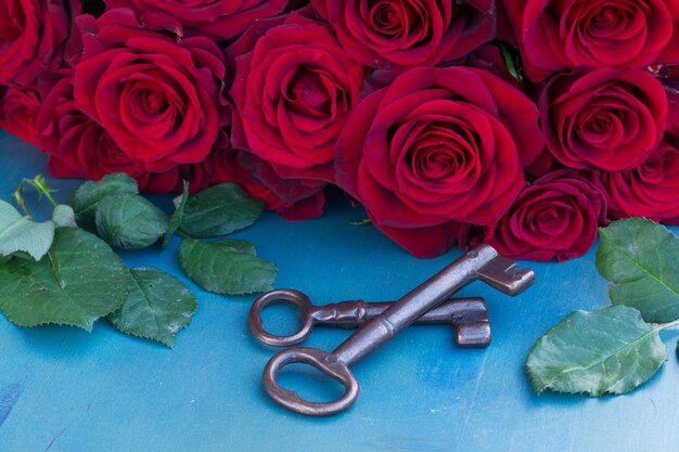 Clés Avec Roses Cramoisies Sur Table Bleue