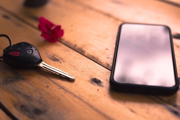 Clés de télécommande de téléphone portable et de voiture sur fond de bois