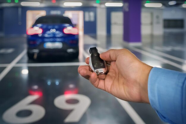 Photo clés de voiture dans une main de la personne dans le contexte du parking souterrain de la voiture