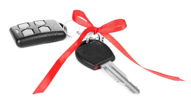 Des clés de voiture avec un nœud rouge comme présent isolées sur blanc