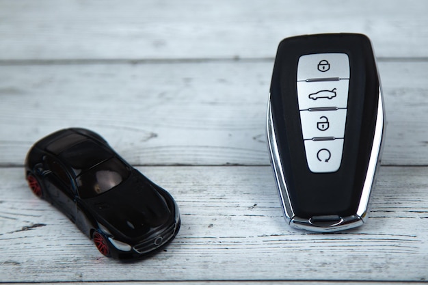 Les clés de la voiture sont noires avec des inserts métalliques et des boutons automatiques sur un fond de bois blanc