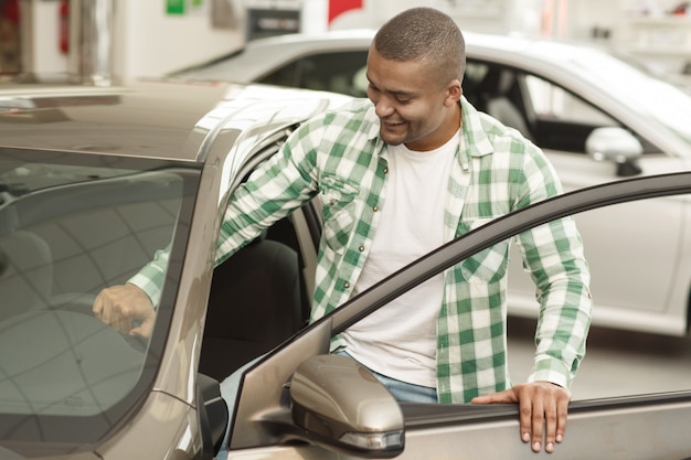 Un client attrayant qui monte dans une nouvelle voiture et choisit l’automobile à acheter.