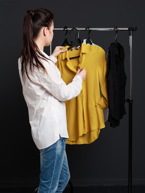 Le Client Choisit Les Vêtements. Jeune Femme En Blouse Blanche