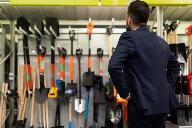 Un client dans un magasin de jardinage choisit une nouvelle pelle