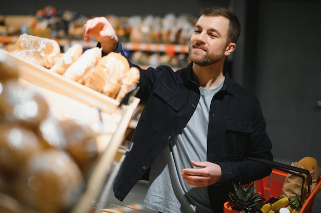 Client Dans Un Supermarché Homme Faisant Des Courses D'épicerie Debout Avec Un Panier Choisir Un Produit Alimentaire à L'intérieur Guy Acheter Des Produits D'épicerie Dans Un Magasin D'alimentation Mise Au Point Sélective Copier L'espace