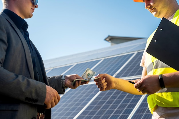 Client donnant de l'argent au travailleur pour une installation réussie de panneaux solaires