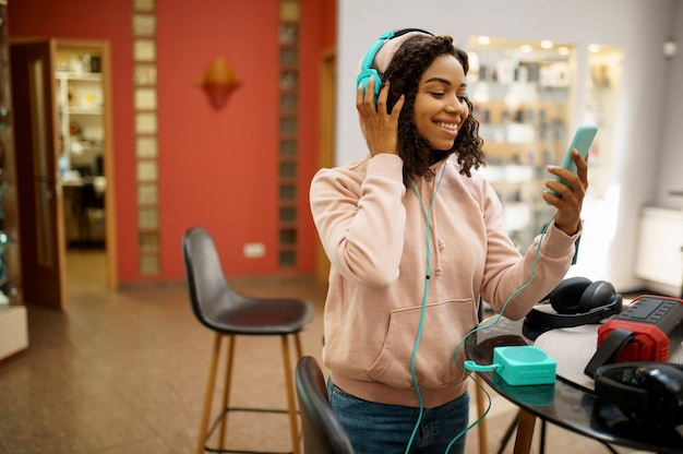 Photo client essayant des écouteurs dans un magasin audio, fan de musique. personne de sexe féminin dans un magasin de musique, vitrine avec écouteurs, acheteur en magasin multimédia