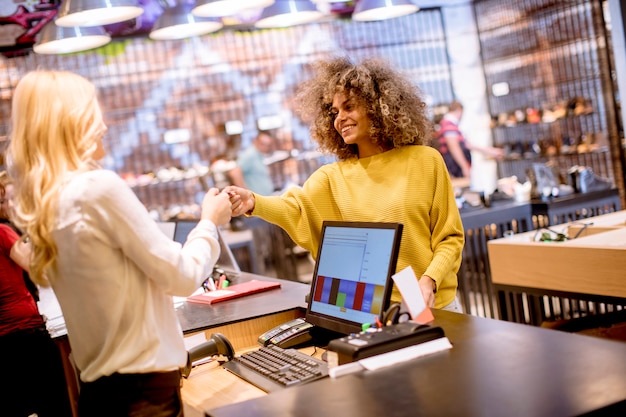 Client de femme heureuse de payer par carte de crédit dans le showroom de la mode