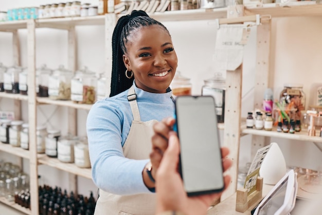 Client femme noire et paiement avec écran de smartphone finance et machine pour la transaction dans un magasin assistant de magasin d'affaires et employé avec client téléphone portable et technologie avec service