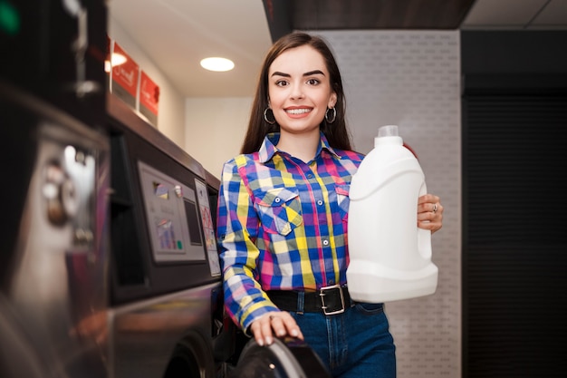 Client de laverie tenant une bouteille de détergent à lessive.