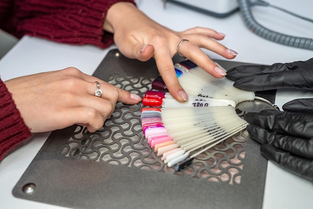 Client avec maître choisissant le vernis à ongles de couleur dans le cabinet de manucure et de pédicure