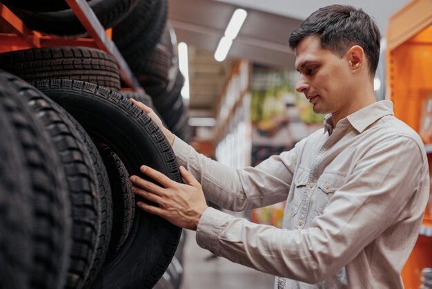 Client masculin choisissant de nouveaux pneus dans le supermarché