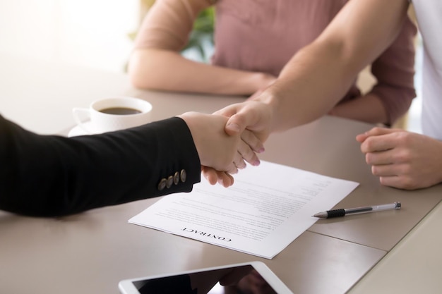 Client masculin et courtier d'assurance féminin se serrant la main couple et agent immobilier se serrant la main après la signature du document gros plan de faire affaire avec des clients satisfaits contrat avec une entreprise