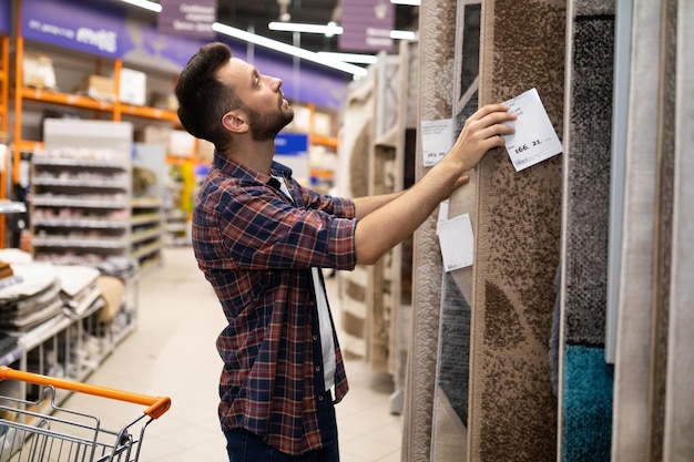 Un client masculin dans une quincaillerie choisit un grand tapis