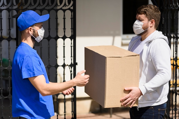 Client avec masque facial recevant un colis du livreur