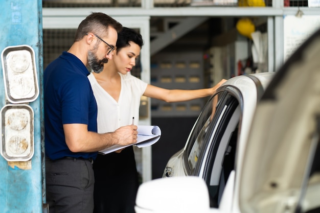 Le Client Mécanicien Et Femme Vérifie L'état De La Voiture Avant La Livraison. Garage De Station D'entretien De Réparation Automobile.