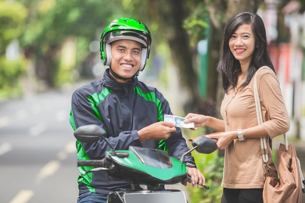 Le client paie pour son trajet jusqu'au chauffeur de taxi moto