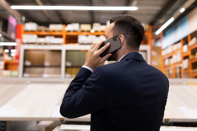 Un client parle au téléphone dans le service des revêtements de sol d'un hypermarché