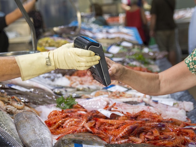 Client payant au marché des fruits de mer Mise au point douce sur le terminal de carte à main