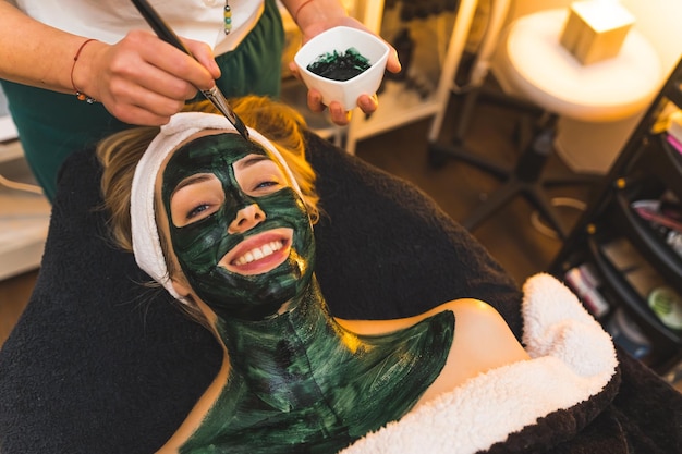 Client recevant son soin du visage auprès d'un cosmétologue professionnel dans un spa