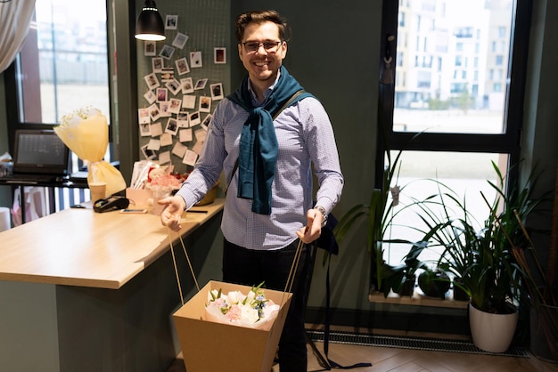 Photo client satisfait avec un bouquet de fleurs emballé en regardant la caméra avec un sourire