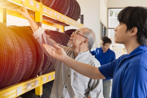 Le client sélectionne des pneus de voiture dans le garage et le personnel de vente recommande divers types de pneus de véhicule