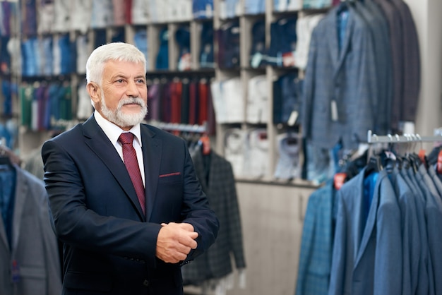 Client senior ramassant des costumes en magasin