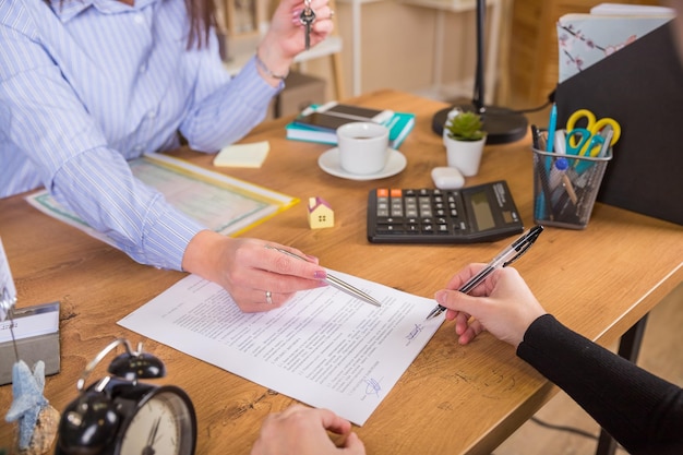 Le client signe un document concernant l'activité immobilière à côté d'un avocat ou d'un agent immobilier assis au bureau Concept d'entreprise de vente et d'achat de maison